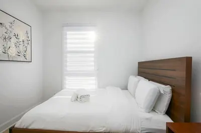 a bedroom with a white bed with a wooden headboard at Contemporary 2BR Retreat in MTL Village in Montréal