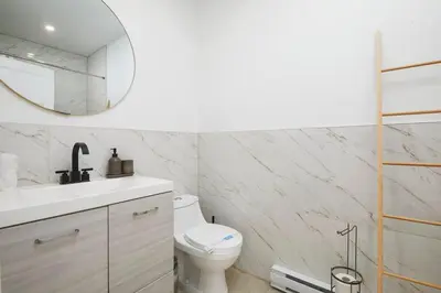 a white bathroom with a toilet and a mirror at Contemporary 2BR Retreat in MTL Village in Montréal