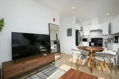a living room with a large television and a wooden table at Contemporary 2BR Retreat in MTL Village in Montréal
