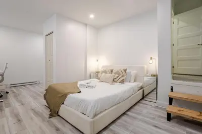 a white bedroom with a large bed and a dresser at Delightful 2BR in Village Downtown in Montréal