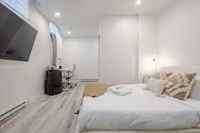 a white bedroom with a large bed and a flat screen tv at Delightful 2BR in Village Downtown in Montréal