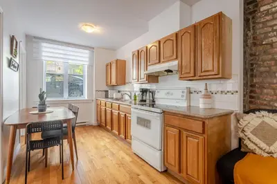 a kitchen with wooden cabinets and a table and a table and a chair at Elegant 4 Bedroom residence in downtown MTL in Montréal