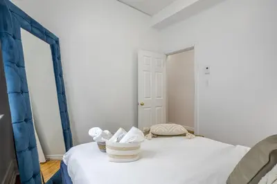 a bedroom with a bed with white sheets and a mirror at Chic 4BR Haven Sunlit in Downtown MTL in Montréal