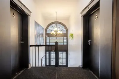 a hallway with a black door and a chandelier at Chic 4BR Haven Sunlit in Downtown MTL in Montréal