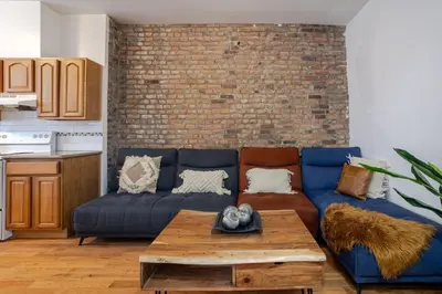 a living room with a blue couch and a brick wall at Chic 4BR Haven Sunlit in Downtown MTL in Montréal