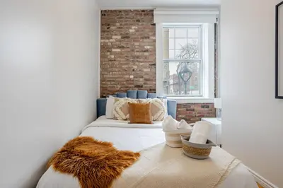 a bedroom with a bed and a brick wall at Chic 4BR Haven Sunlit in Downtown MTL in Montréal