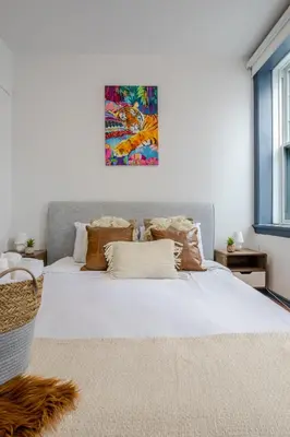 a bedroom with a large white bed with a painting on the wall at Prime Location Charming 4BR in Downtown MTL in Montréal