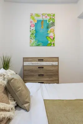 a bedroom with a bed with a dresser and a painting at Prime Location Charming 4BR in Downtown MTL in Montréal