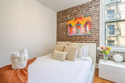 a bedroom with a white bed and a brick wall at Prime Location Gorgeous 4BR Downtown MTL in Montréal