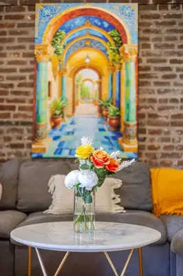 a vase of flowers on a table in front of a painting at Prime Location Gorgeous 4BR Downtown MTL in Montréal