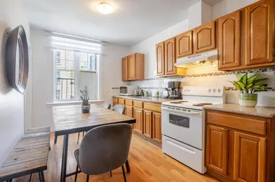 a kitchen with wooden cabinets and a table with chairs at Prime Location Gorgeous 4BR Downtown MTL in Montréal