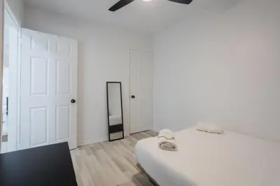 a white bedroom with a bed and a mirror at Excellent 4 Bedroom in Griffintown Downtown MTL in Montréal