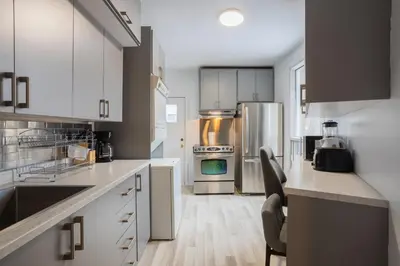 a kitchen with white cabinets and stainless steel appliances at Excellent 4 Bedroom in Griffintown Downtown MTL in Montréal