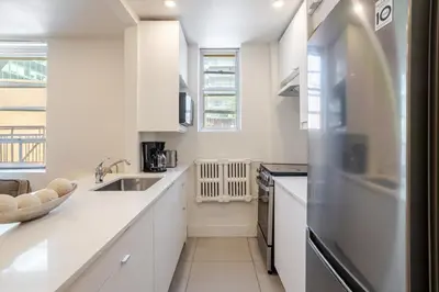 a kitchen with white cabinets and a sink at Downtown Hideaway Peaceful and Trendy in Montréal