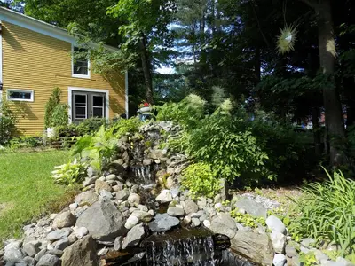 a garden with a waterfall in front of a house at À L'Ancestrale B&B in Magog-Orford