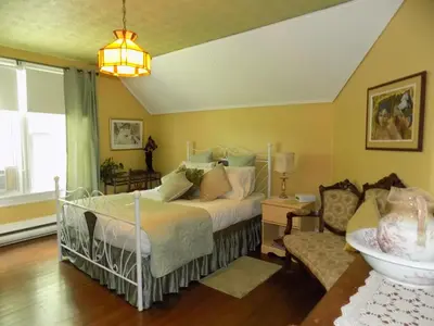 a bedroom with a bed and a chair at À L'Ancestrale B&B in Magog-Orford