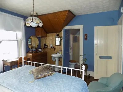 a bedroom with blue walls and a bed and a sink at À L'Ancestrale B&B in Magog-Orford