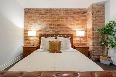 a bedroom with a large bed with a brick wall at Chic DT MTL Condo with Rooftop, BBQ in Montréal
