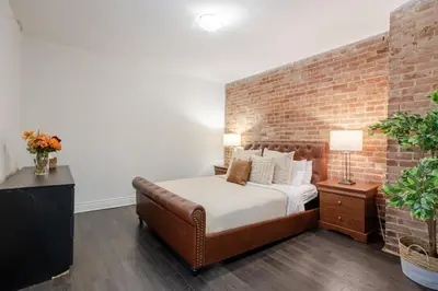 a brick walled bedroom with a bed and a couch at Chic DT MTL Condo with Rooftop, BBQ in Montréal