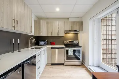 a kitchen with wooden cabinets and stainless steel appliances at Chic DT MTL Condo with Rooftop, BBQ in Montréal