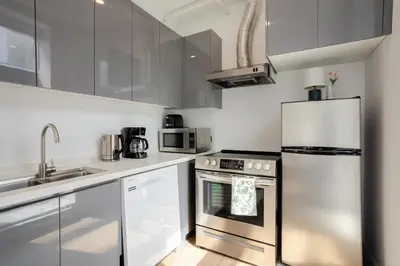 a kitchen with white cabinets and a stainless steel refrigerator at Urban Studio on Bishop Hot Spot Dtown MTL in Montréal
