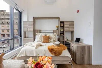 a bedroom with a bed and a desk with a laptop at Lovely Loft with Views on Bishop - MTL in Montréal