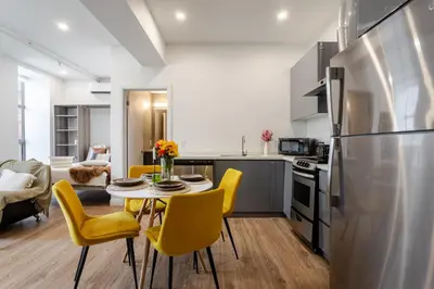 a kitchen and dining room with a table and yellow chairs at Modern 1BDR Apartment on Bishop - MTL in Montréal