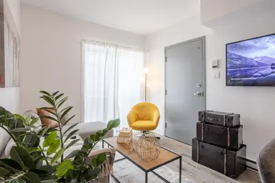 a living room with a yellow chair and a table at Urban 1BDR Apartment on Bishop -MTL Live Spot in Montréal