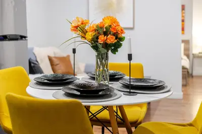 a table with plates and a vase of orange flowers at Charming 1BDR Apartment on Bishop St- MTL in Montréal
