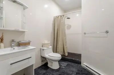 a white bathroom with a toilet and a shower at 1BDR Mezzanine-Bishop-Vibe Central MTL in Montréal