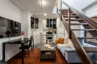 a kitchen and living room with a couch and a table at 1BDR Mezzanine-Bishop-Vibe Central MTL in Montréal