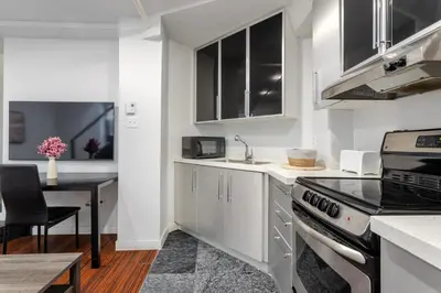 a kitchen with white cabinets and a stove top oven at 1BDR Mezzanine-Bishop-Vibe Central MTL in Montréal