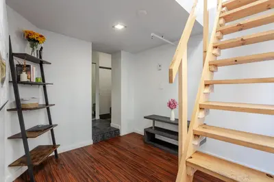 a staircase in a living room with white walls and wooden floors at Spacious 1BDR Mezzanine on Bishop Central MTL in Montréal