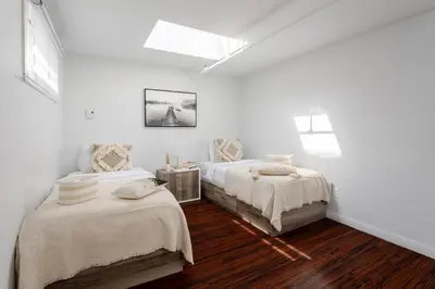 two beds in a room with white walls and wood floors at Spacious 1BDR Mezzanine on Bishop Central MTL in Montréal