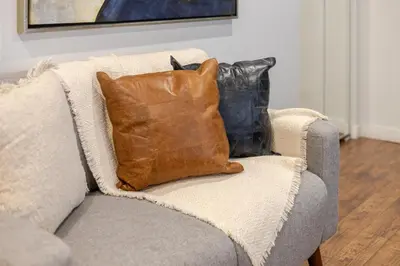 a brown pillow sitting on a gray couch at Spacious Studio on Bishop - Hot Spot Dtown MTL in Montréal
