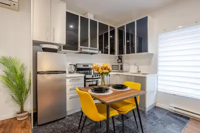 a kitchen with a wooden table and yellow chairs at Spacious Studio on Bishop - Hot Spot Dtown MTL in Montréal