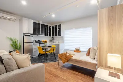 a living room with a couch and a kitchen at Spacious Studio on Bishop - Hot Spot Dtown MTL in Montréal