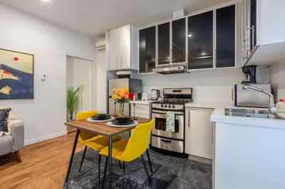 a kitchen with a wooden table and yellow chairs at Spacious Studio on Bishop - Hot Spot Dtown MTL in Montréal