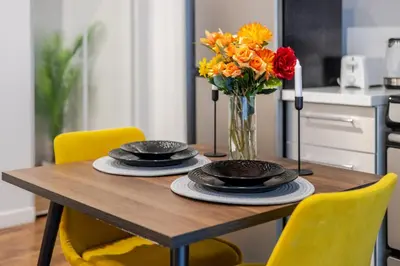 a wooden table with yellow chairs and a vase of flowers at Spacious Studio on Bishop - Hot Spot Dtown MTL in Montréal