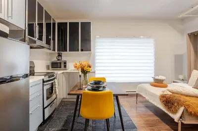 a kitchen with a table and yellow chairs at Spacious Studio on Bishop - Hot Spot Dtown MTL in Montréal