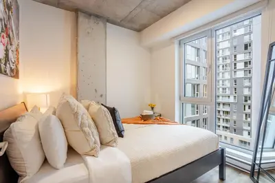 a bedroom with a white bed and a large window at Stylish 1BDR Apartment in the Heart of DT MTL in Montréal