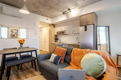 a living room with a couch and a table with a laptop at Stylish 1BDR Apartment in the Heart of DT MTL in Montréal