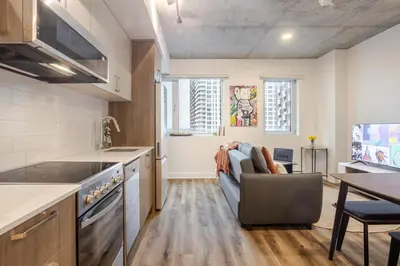 a kitchen and living room with a couch and a table at Stylish 1BDR Apartment in the Heart of DT MTL in Montréal