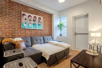 a living room with a couch and a brick wall at Central 2BDR Condo on Bishop-Vibe Central MTL in Montréal