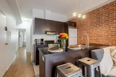 a kitchen with a sink and a brick wall at Central 2BDR Condo on Bishop-Vibe Central MTL in Montréal