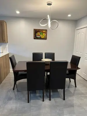 a dining room table with black chairs and a chandelier at Luxieux Appartement laval in Laval