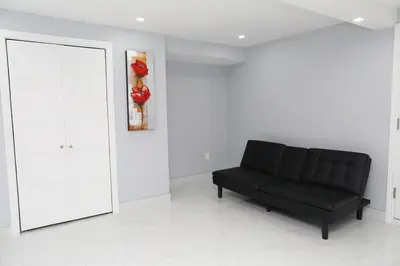 a black couch in a white room with a painting at Appartement 3 chambres avec SOUS-SOL in Laval