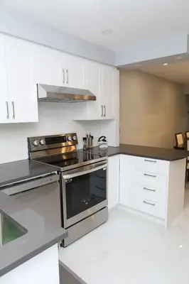 a kitchen with white cabinets and a stove top oven at Appartement 3 chambres avec SOUS-SOL in Laval