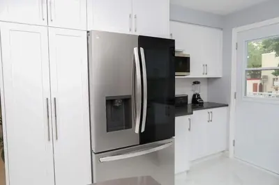 a kitchen with a stainless steel refrigerator and white cabinets at Appartement 3 chambres avec SOUS-SOL in Laval