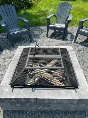 two chairs and a fire pit with a metal grate at Comme chez soi in Granby